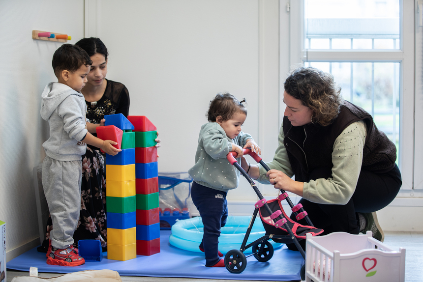 Une maman joue avec ses enfants avec une éducatrice.