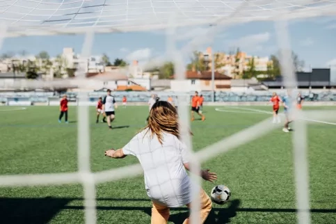 Des enfants jouent au football dans un city stade. 