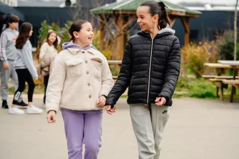 Deux adolescentes discutent joyeusement dans la cour du collège.