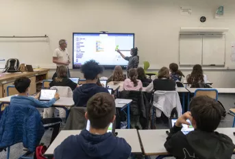 jeunes devant un écran dans une salle de classe