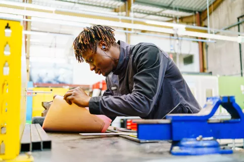 Un jeune homme travaille sur un établi.