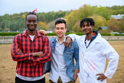 3 jeunes hommes prennent la pose et sourient.