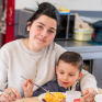 Une jeune femme s'occupe de donner à manger à un enfant de maternelle